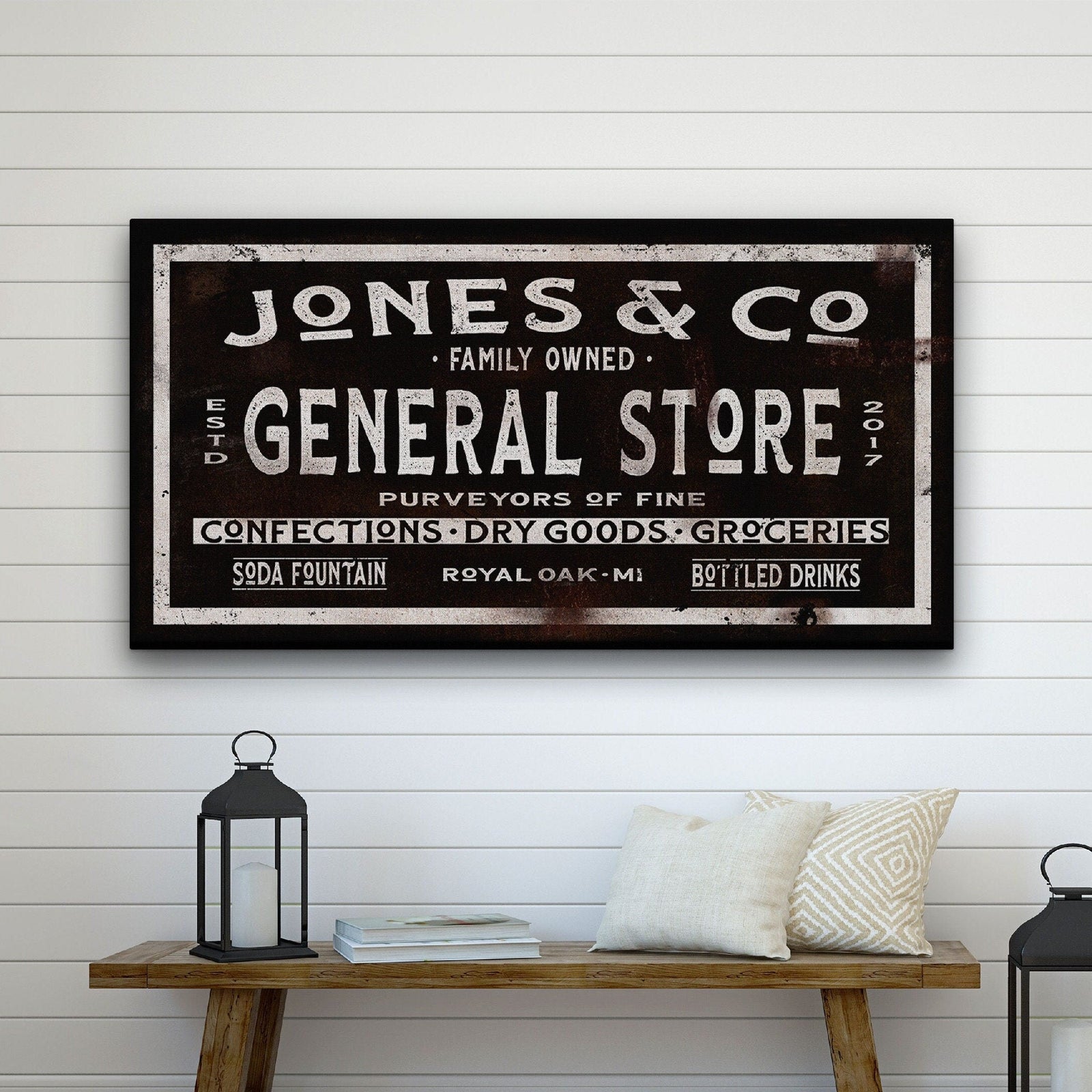 Heritage Store Canvas showing "Jones & Co · Family Owned · General Store Est. 2017" with "Royal Oak · MI" on a heavily distressed black background with vintage cream lettering, mounted on a shiplap wall above a rustic wooden bench