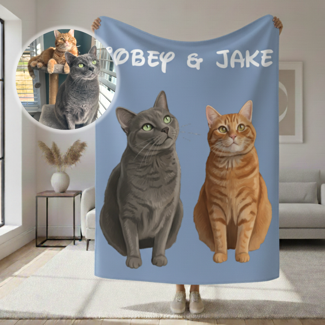 Blue sherpa blanket printed with cartoon portraits of two cats and personalized text "OBEY & JAKE" at the top, displayed indoors with a circular photo inset showing the original pet photos used for the design.