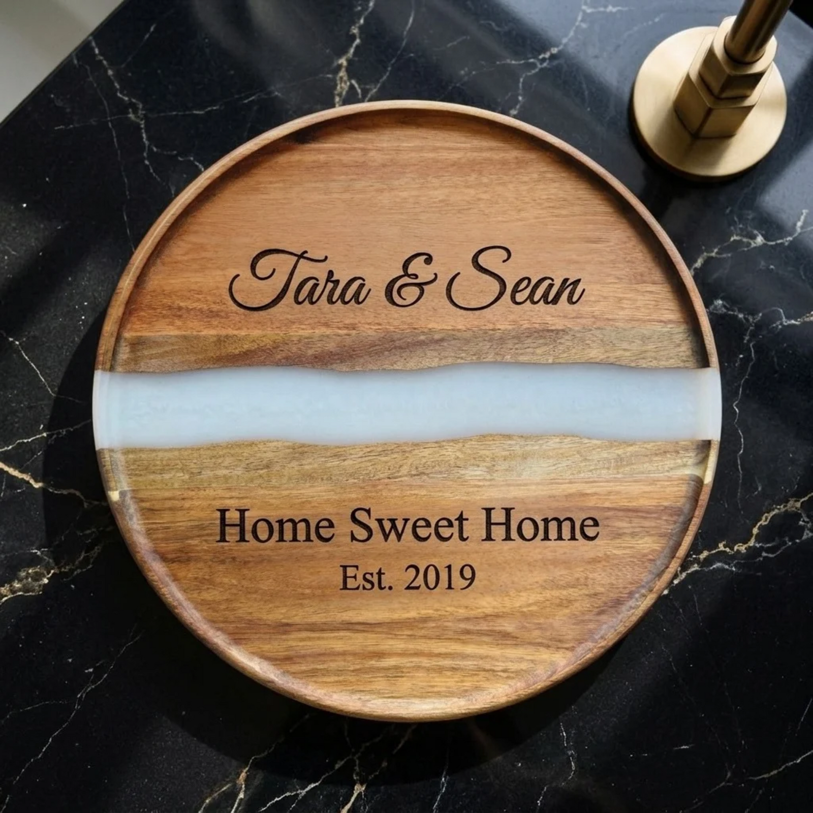 Personalized round acacia charcuterie board with a pearl white resin river, engraved Tara & Sean in script with Home Sweet Home and Est. 2019