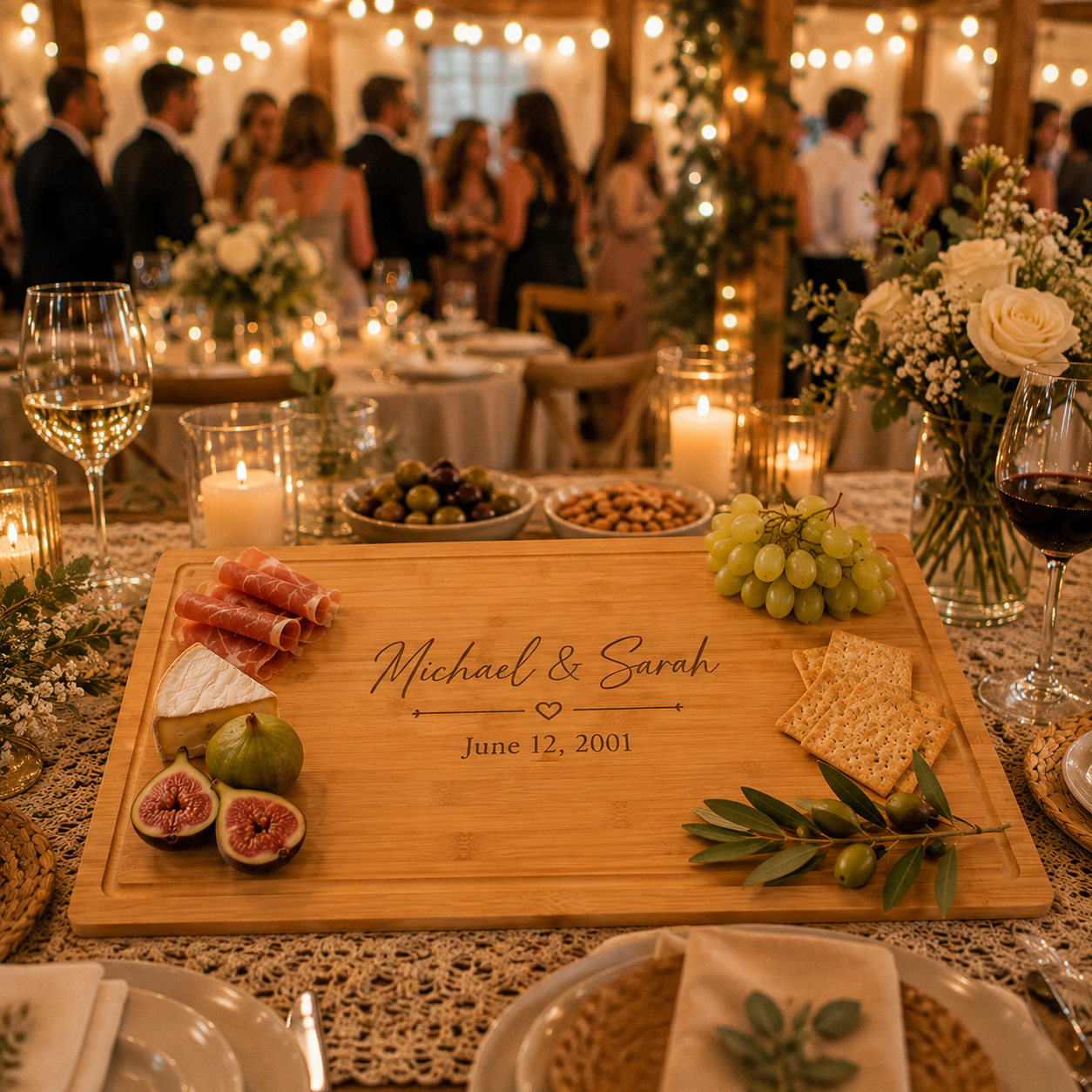 Bamboo wedding serving board engraved Michael & Sarah June 12, 2001 with prosciutto, brie, figs, grapes and crackers on a candlelit wedding reception table
