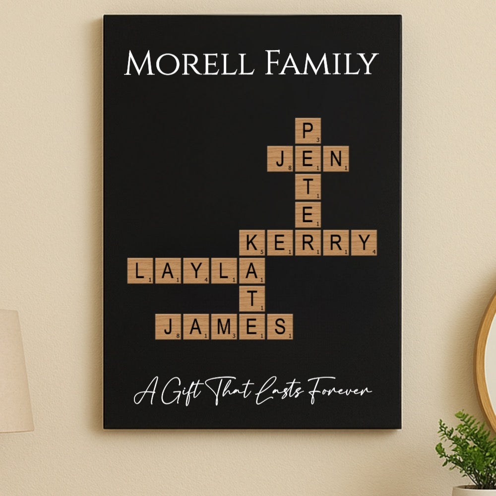 Black wall art with sample family names "MORELL FAMILY" arranged in crossword style using wooden Scrabble-inspired tiles, with tagline "A Gift That Lasts Forever" below.