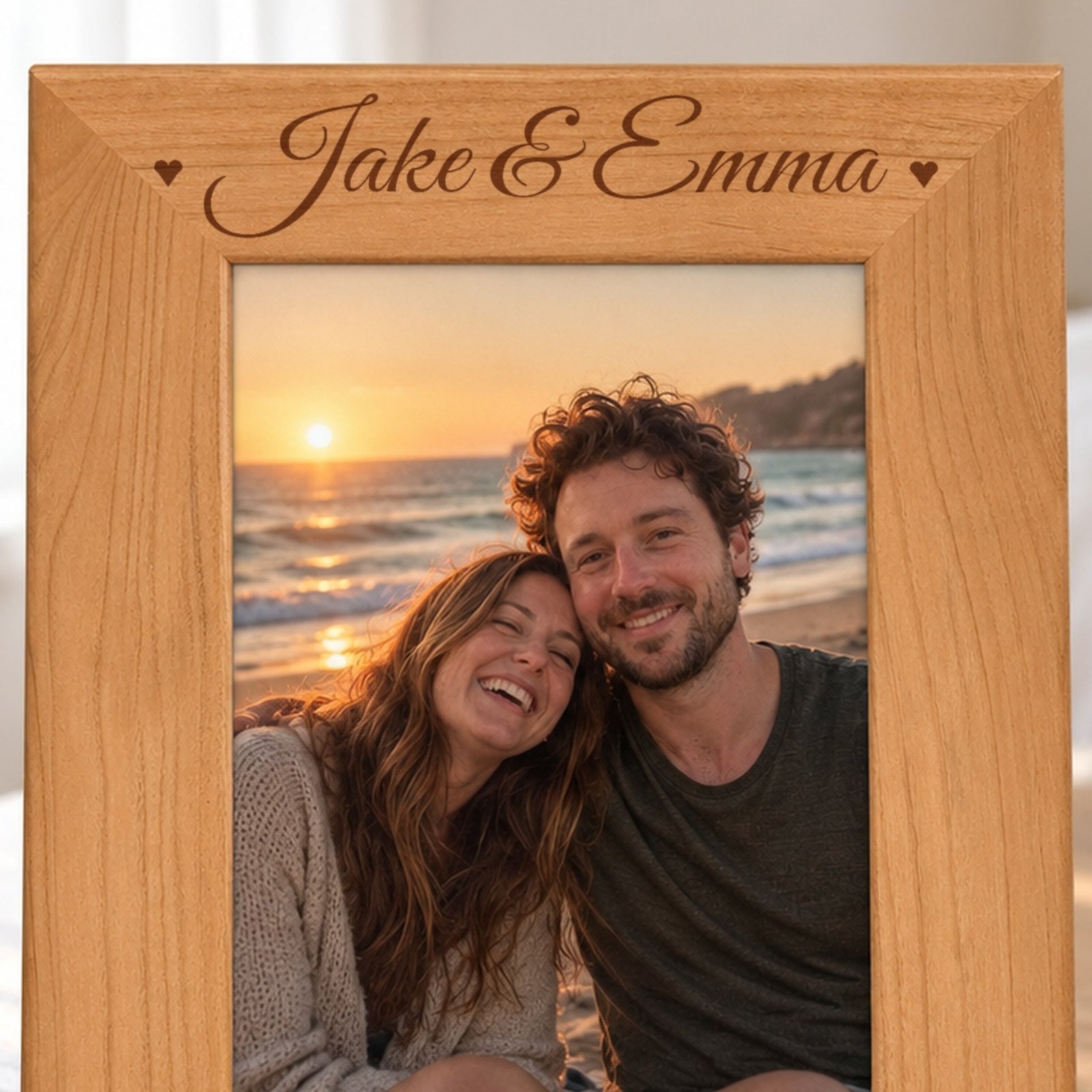 Close-up of the laser engraved names Jake & Emma in script with two hearts on the top border of a red alder couples photo frame