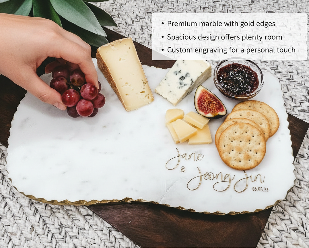 Marble charcuterie board engraved with sample names "Jane & Jeong Jin" and date "03.05.22", styled with cheese, crackers, figs, jam, and grapes.