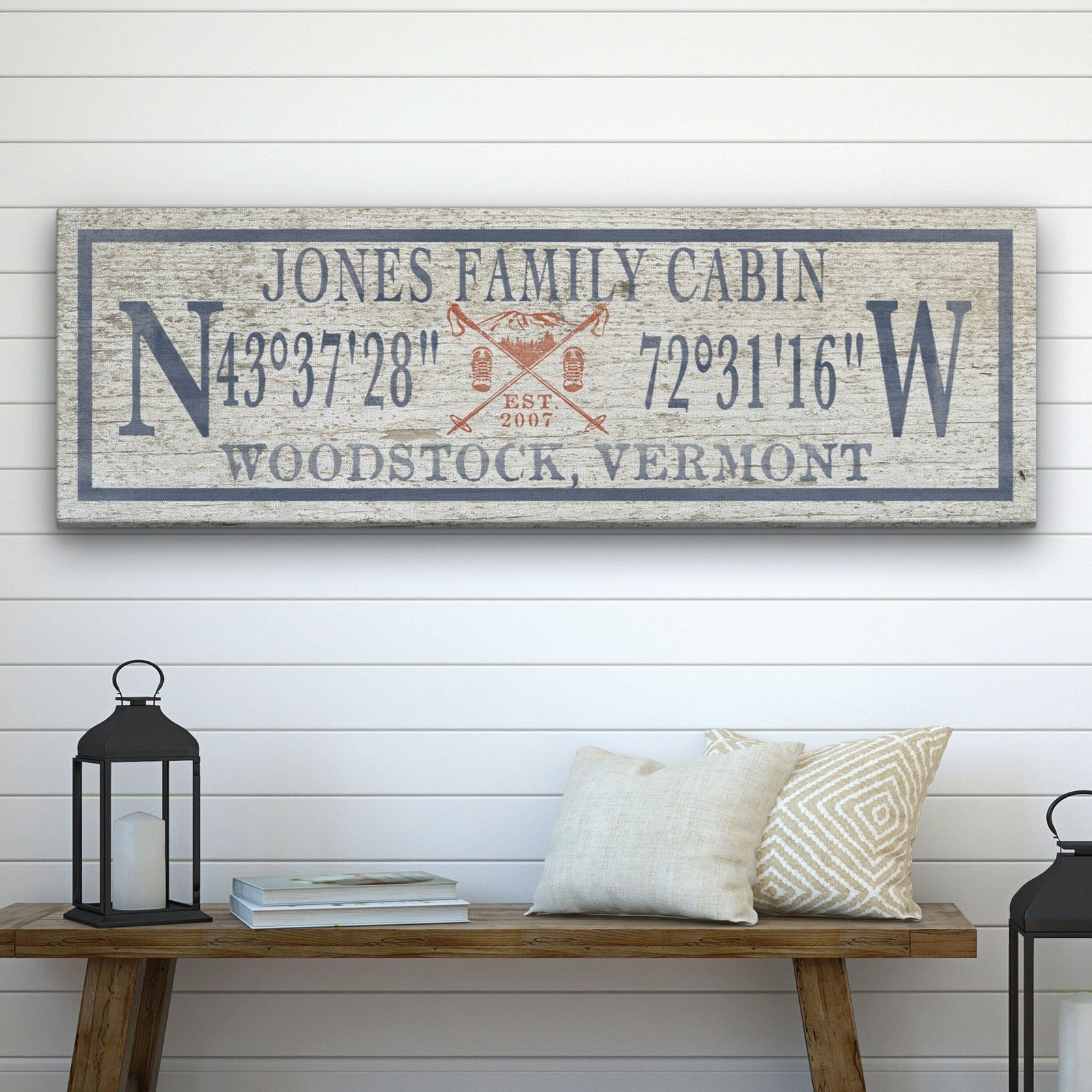 Personalized Canvas Ski Lodge Sign displaying "Jones Family Cabin" above GPS coordinates flanked by large N and W compass letters, with a crossed ski poles and mountain illustration reading "Est. 2007" and "Woodstock, Vermont" at the bottom, on a distressed cream wood background with a slate border