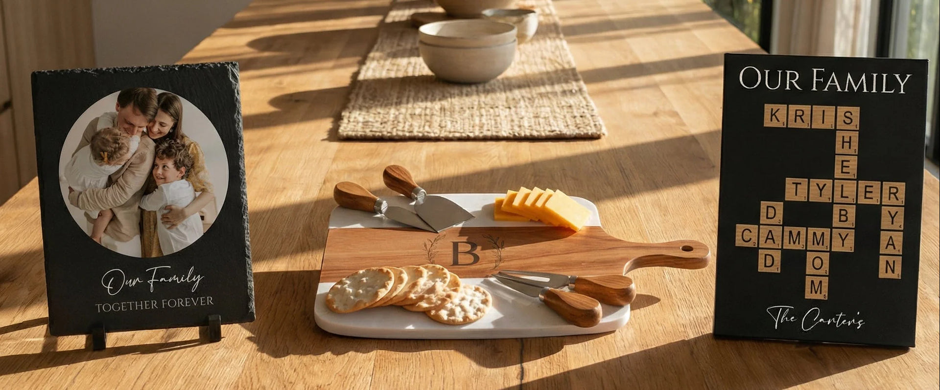 Three personalized housewarming gifts on a sunlit dining. A family photo slate plaque, a monogrammed marble charcuterie board, and a Scrabble Family Name sign handcrafted by Willow & Hive