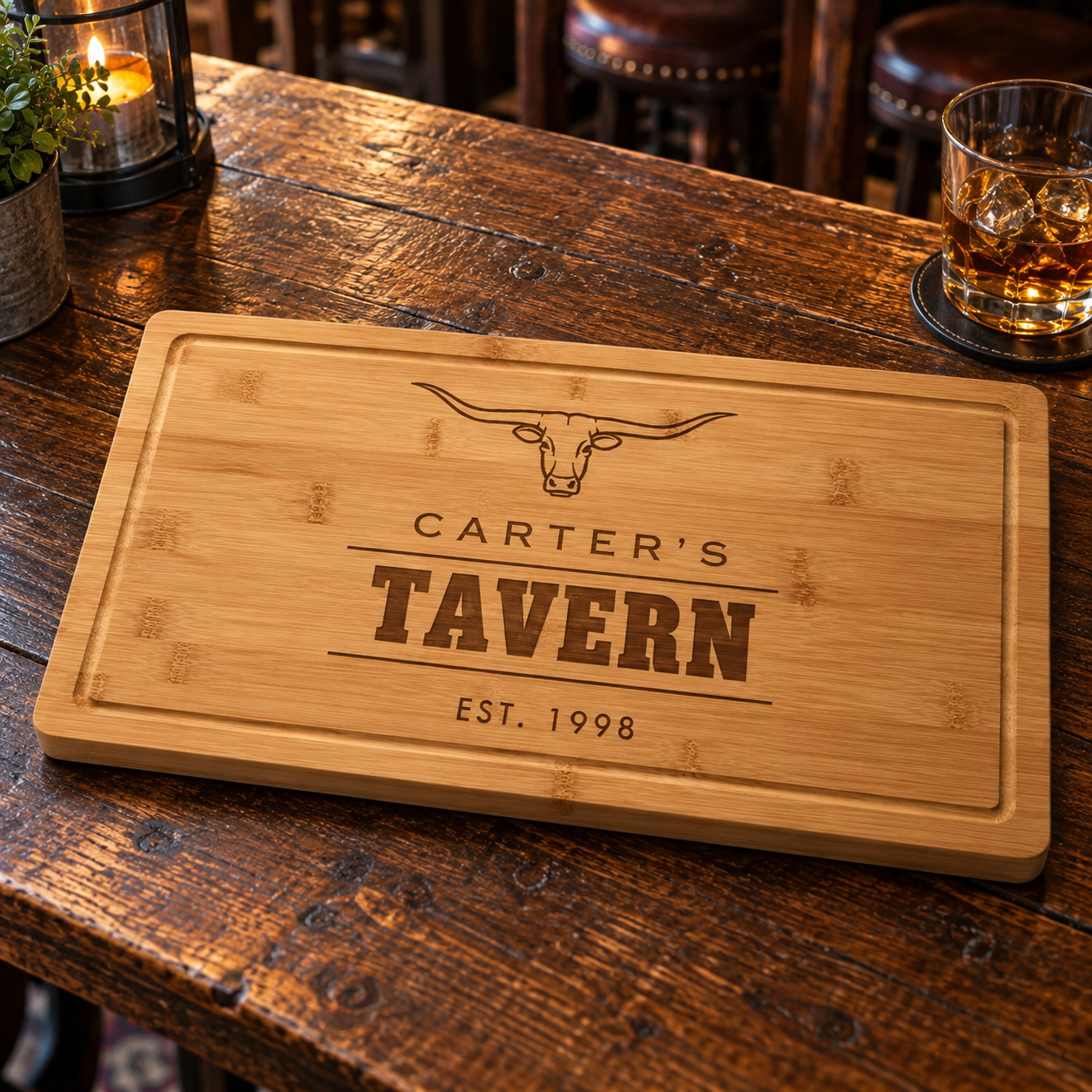 Personalized bamboo steakhouse cutting board engraved with a longhorn steer, CARTER'S TAVERN and EST. 1998, with whiskey glass