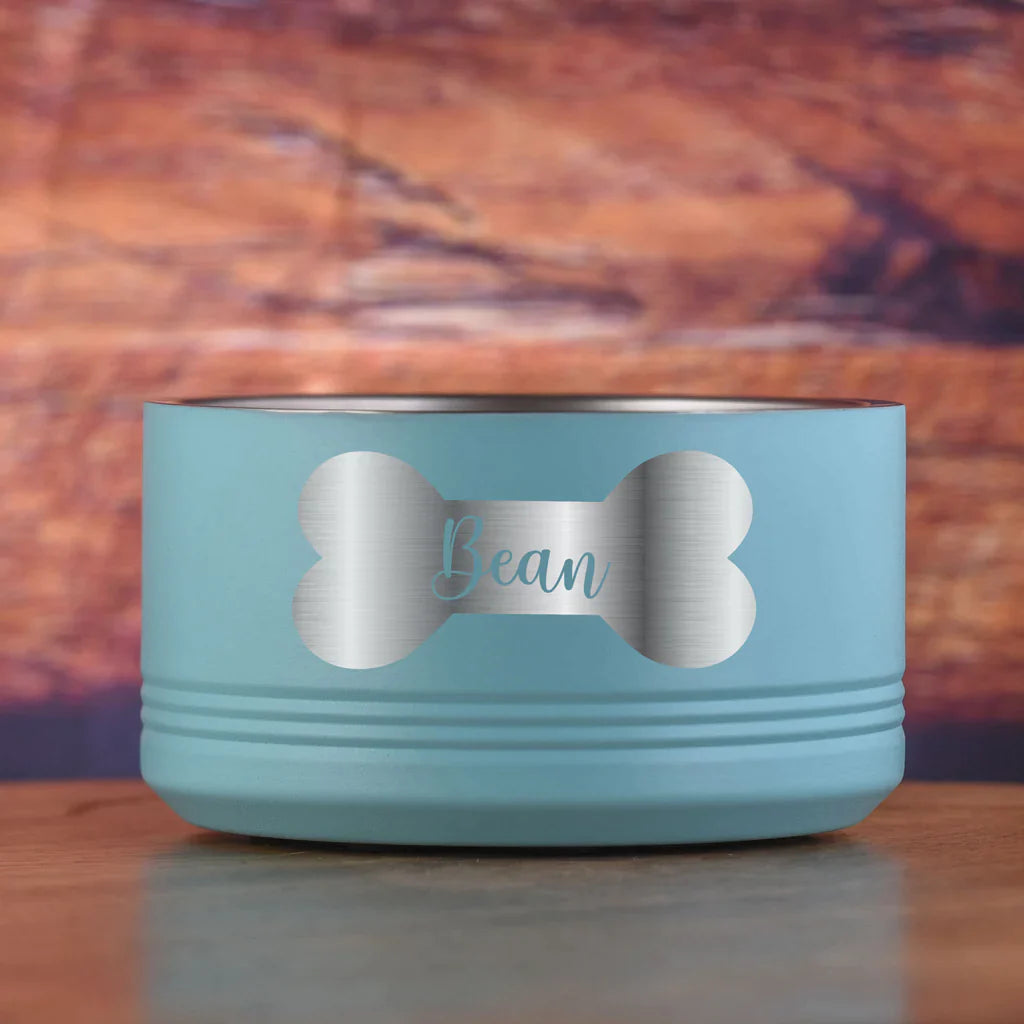 Light blue stainless steel dog bowl with bone-shaped cutout design, engraved with sample name "Bean" in script lettering on the center band.