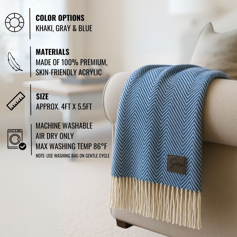 Blue herringbone throw blanket with cream fringe, draped over white chair, showing sample personalization label with name "Sara