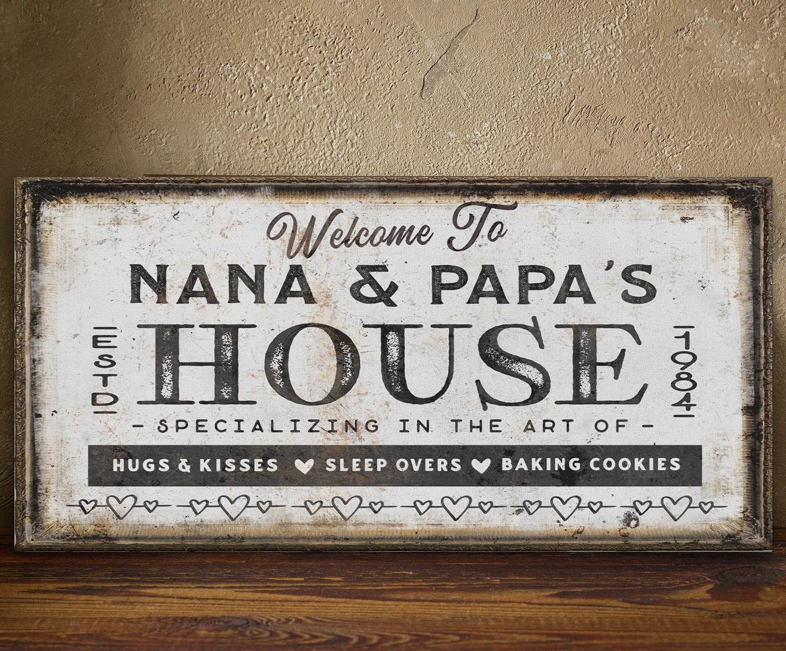 Personalized canvas sign with sample text "Welcome To Nana & Papa's House Est. 1984" in distressed cream and black finish with rustic frame.