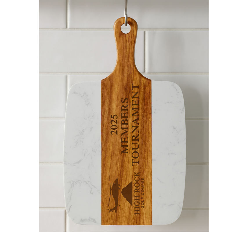 Marble and acacia wood serving board engraved with sample text "2025 MEMBERS TOURNAMENT" and "HIGH ROCK GOLF COURSE" with fish silhouette graphic.