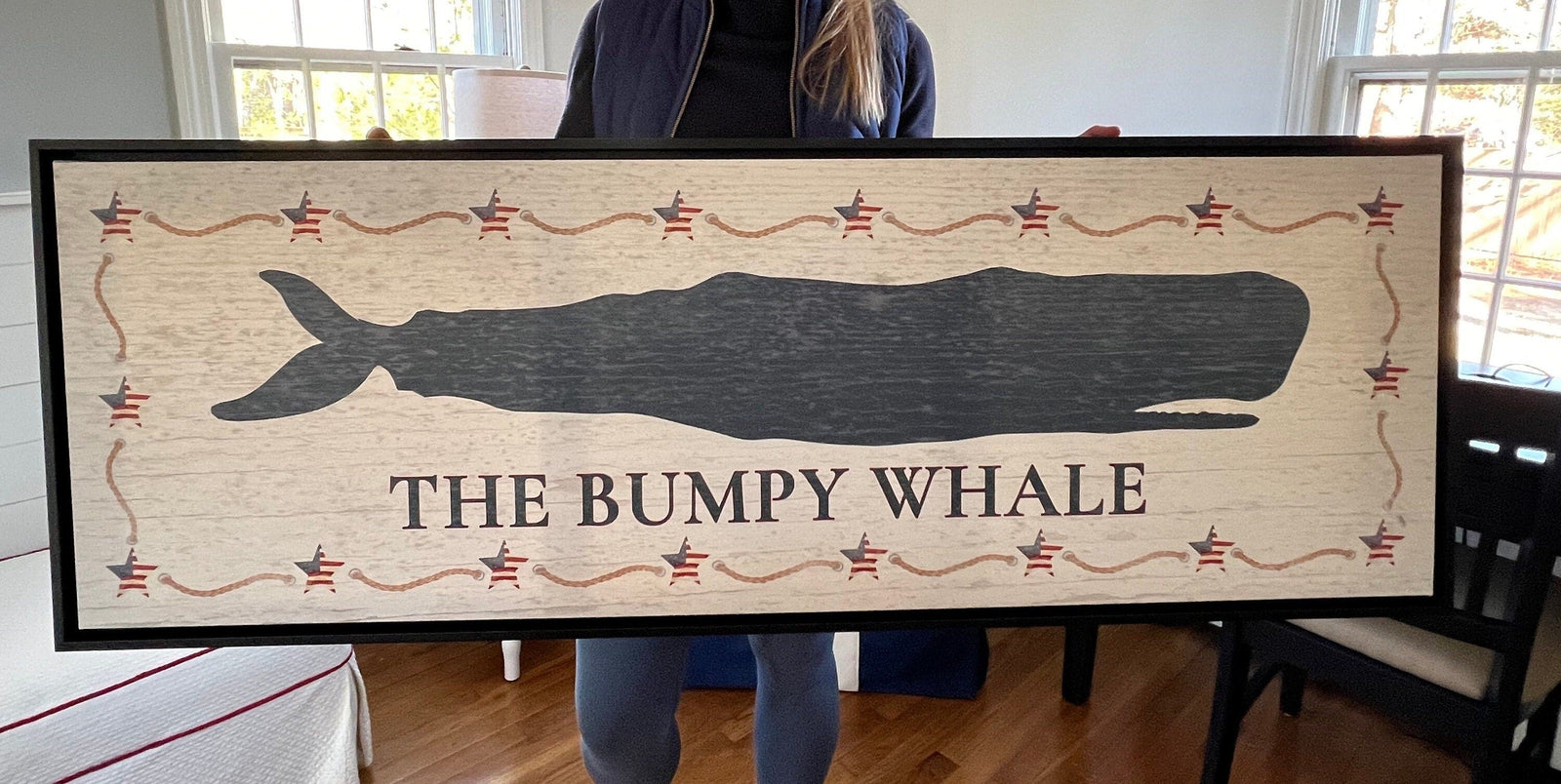 Framed canvas sign with navy whale silhouette, decorative Americana stars and rope border, distressed white wood background, and "THE BUMPY WHALE" text centered below