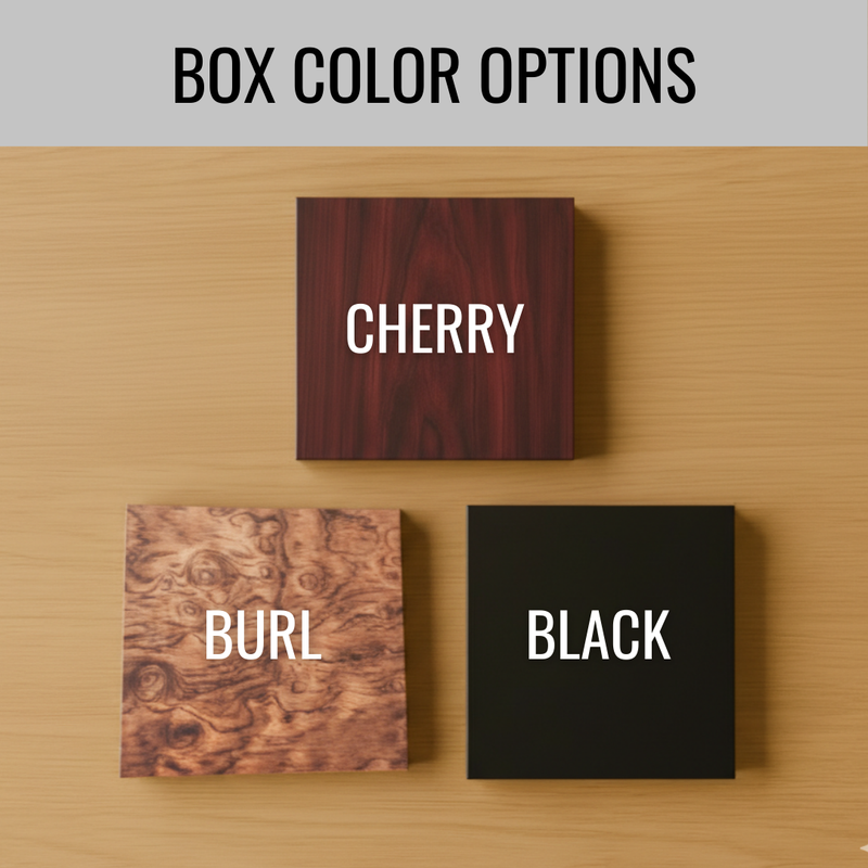 Three wooden box color options displayed on a light wood surface: cherry with deep burgundy wood grain, burl with swirled tan and brown pattern, and black solid finish