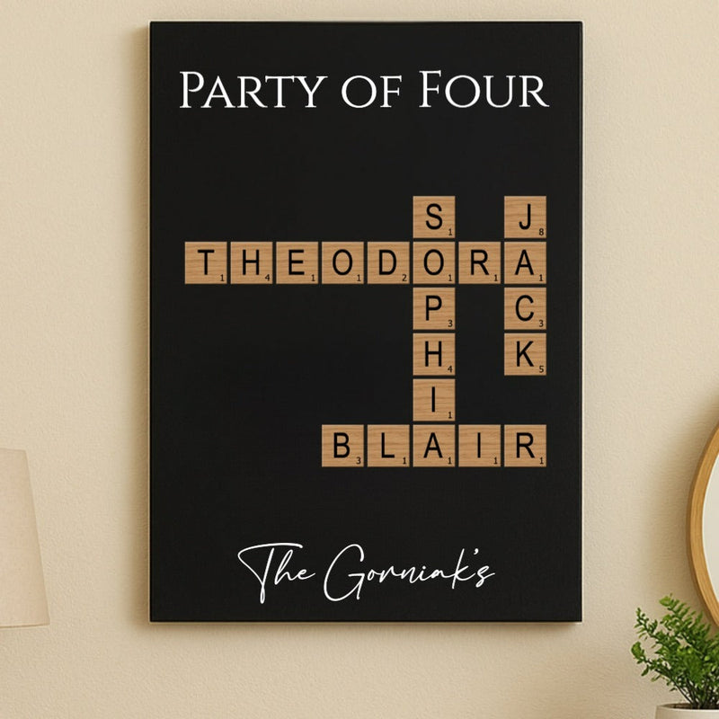 Black wall art displaying "Party of Four" with wooden Scrabble-style tiles showing sample names "Theodora," "Sophia," "Jack," "Sophia," and "Blair" arranged in crossword pattern, personalized family name sign with "The Gorniaks" script at bottom.