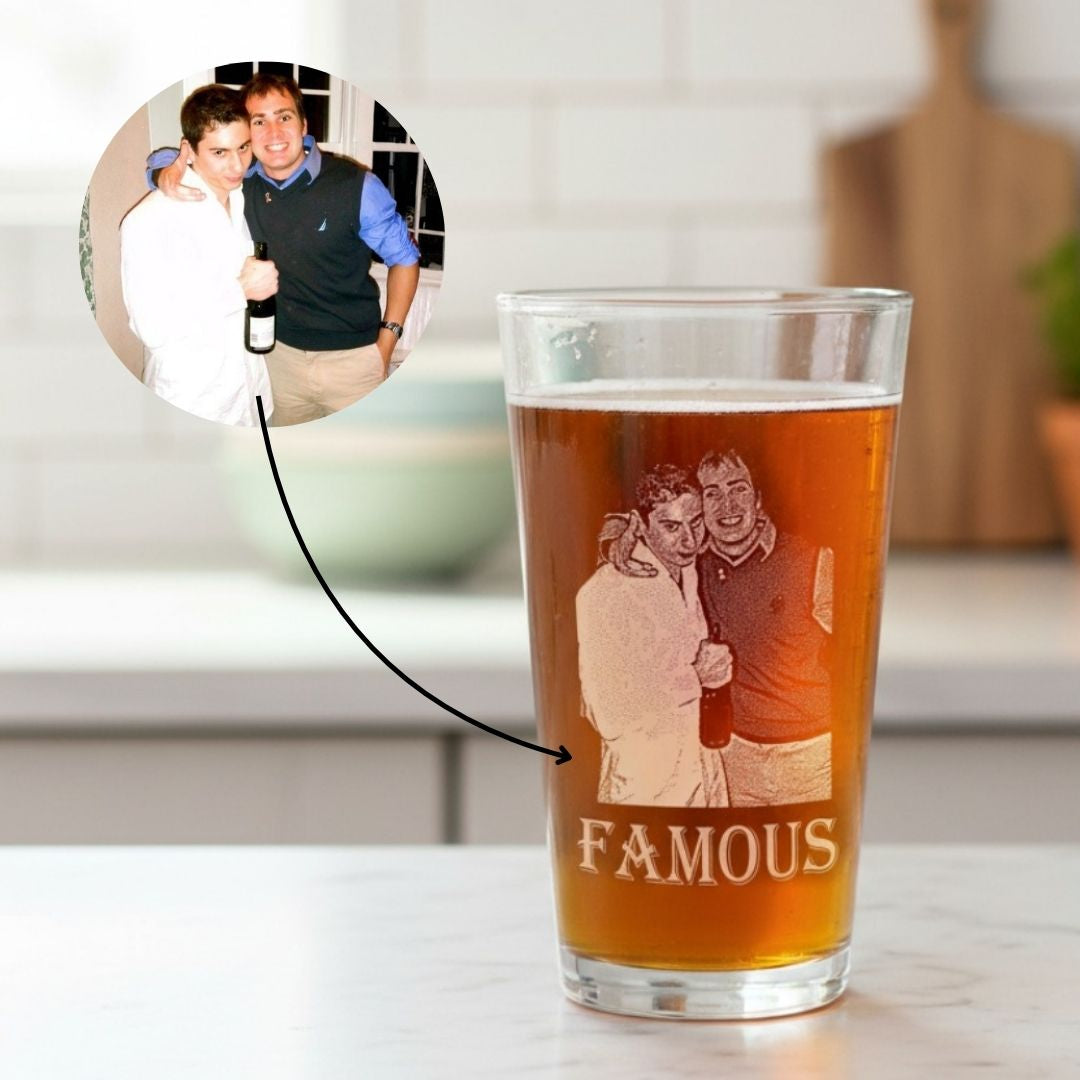 Pint glass filled with amber beer, engraved with sample photo of two men and text "FAMOUS" below, with circular inset showing the original photo used for customization