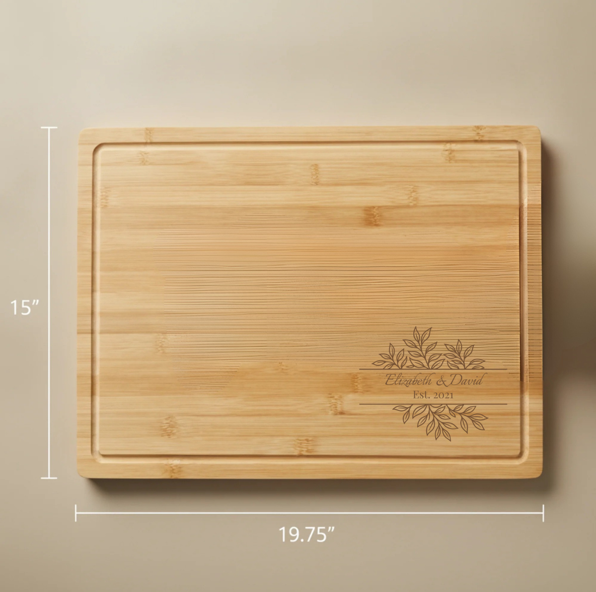 Bamboo cutting board with sample engraving showing "Elizabeth &amp; David" and "Est. 2021" with decorative leaf design, 19.75" by 15