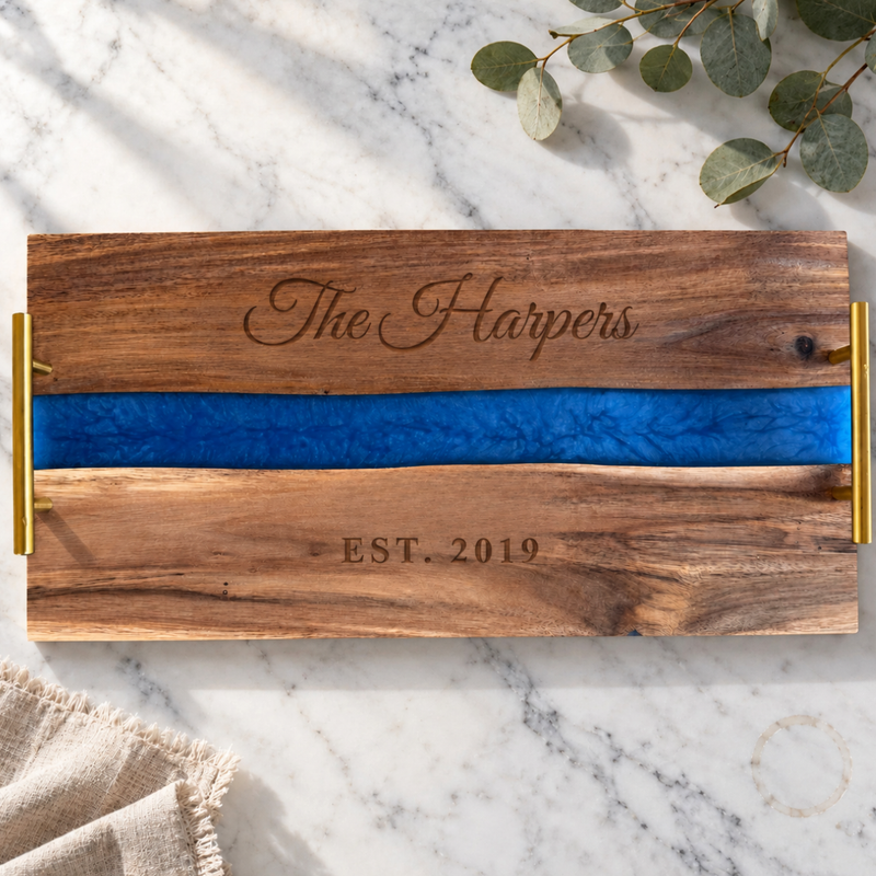 Personalized Blue River Serving Tray engraved The Harpers above a blue pearl resin river and EST. 2019 below, acacia wood with gold handles on white marble