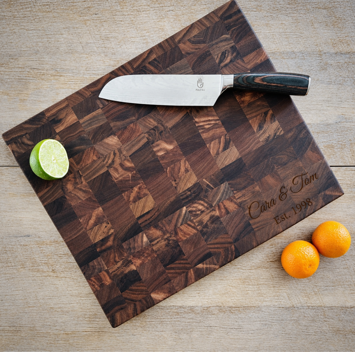 Walnut Custom Butcher Block from above, engraved Cara &amp; Tom and Est. 1998 in the Script Name &amp; Date design, with a chef's knife, lime and oranges