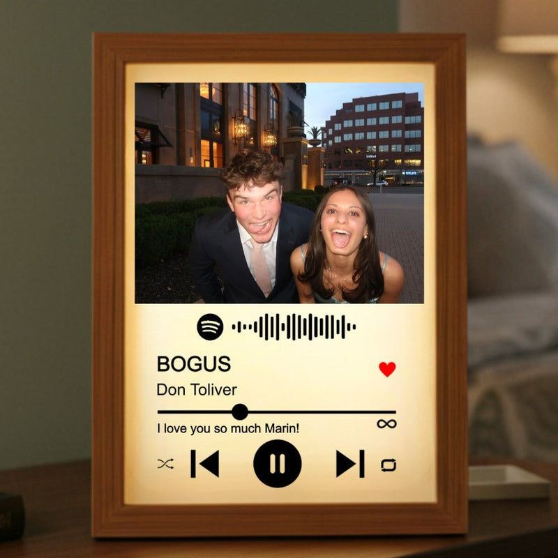 Wood-framed Spotify song plaque displaying a photo of two people with sample song title "BOGUS" by "Don Toliver," sample message "I love you so much Marin!" and scannable Spotify code, illuminated from behind with warm glow.