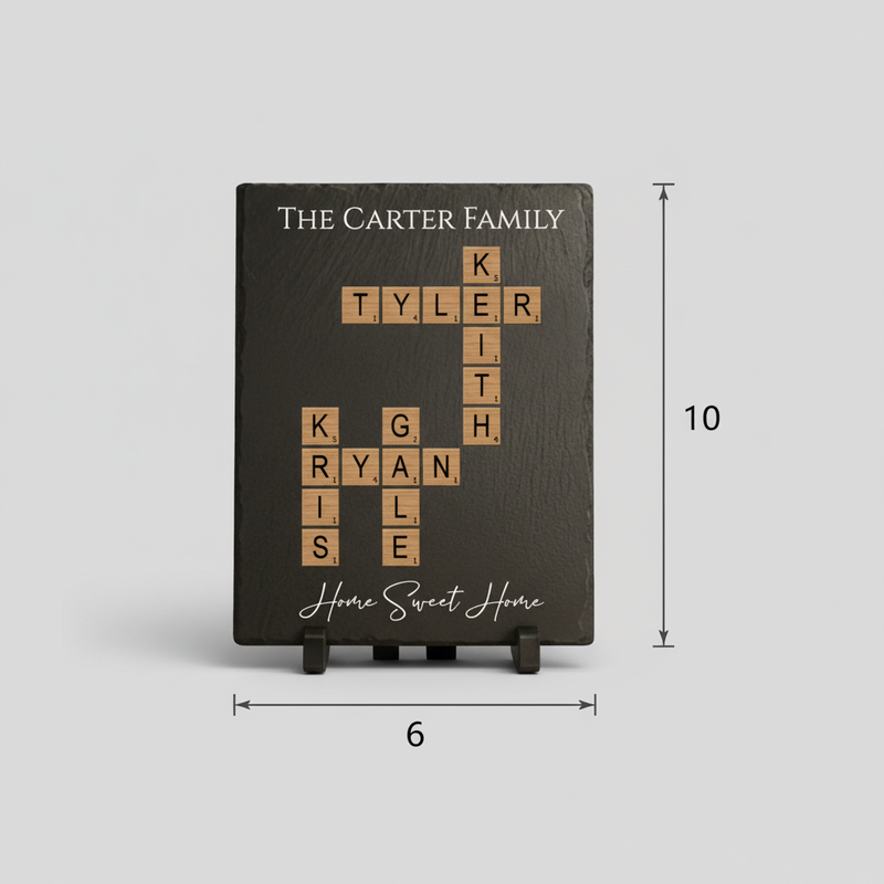 Dark slate board with sample family names "The Carter Family" at top, names arranged in crossword pattern with wood Scrabble tiles below, "Home Sweet Home" script at bottom, shown with dimensions 6 inches wide by 10 inches tall