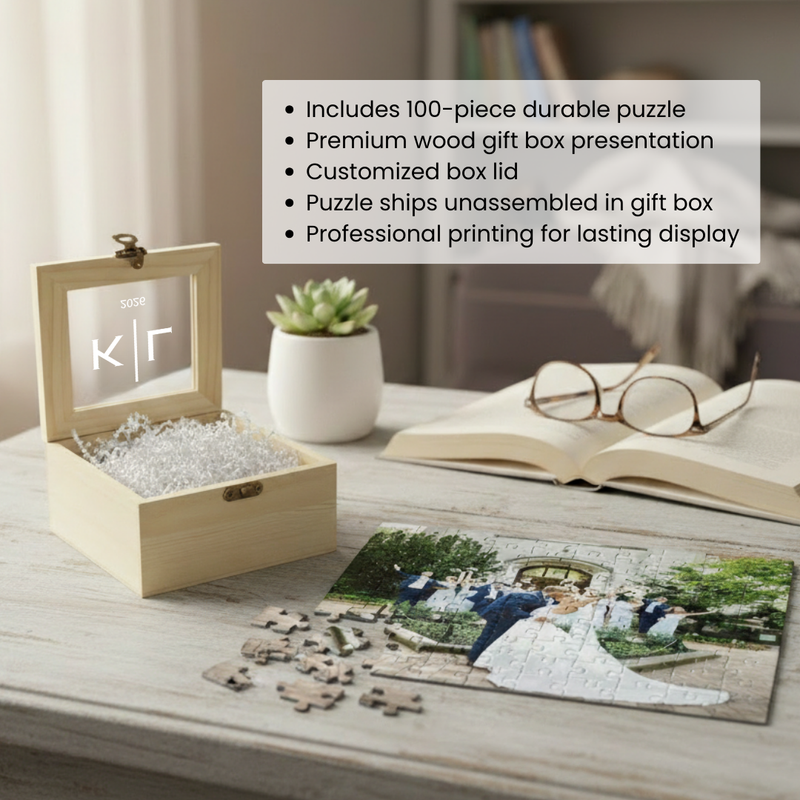 Wooden box with customized lid featuring sample initials, open to reveal packaged 100-piece puzzle and white packing material, displayed with completed puzzle sample showing couple photo