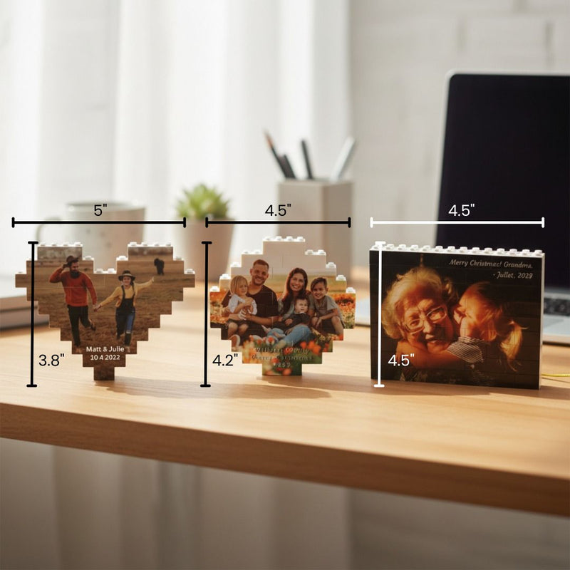 Three wooden building block photo ornaments in different sizes displayed on a desk, with sample photos including a couple with names and date, a family in a pumpkin patch, and a grandmother with grandchildren with "Merry Christmas" text.
