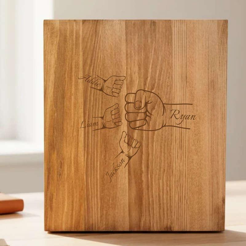 Wooden presentation box lid engraved with fist bump design and sample names "Mike," "Liam," "Ryan," and "Jackson" arranged around the center fists