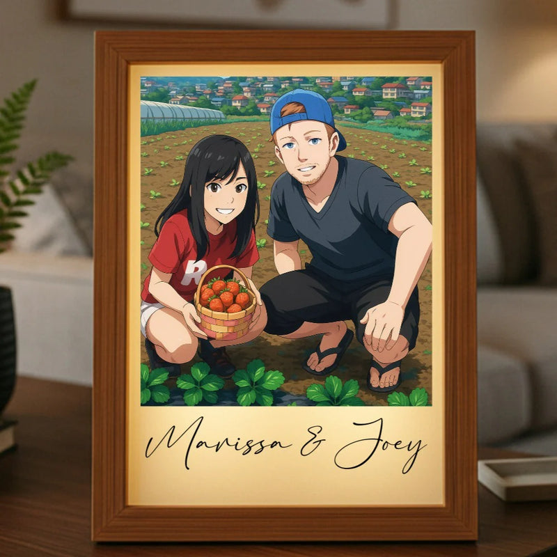 Wood-framed light box displaying anime-style illustration of two people in a vegetable garden holding a basket of tomatoes, with personalized names "Marissa & Joey" printed below the image