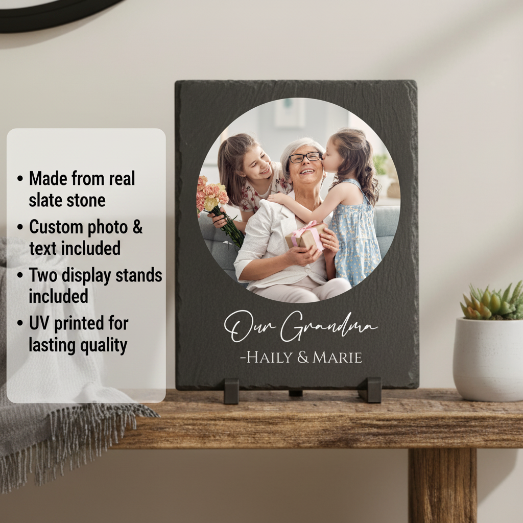 Dark slate plaque with circular photo opening displaying a woman with two children, personalized with sample text "Our Grandma" and names "Haily & Marie" below, displayed on wooden stand with plant nearby