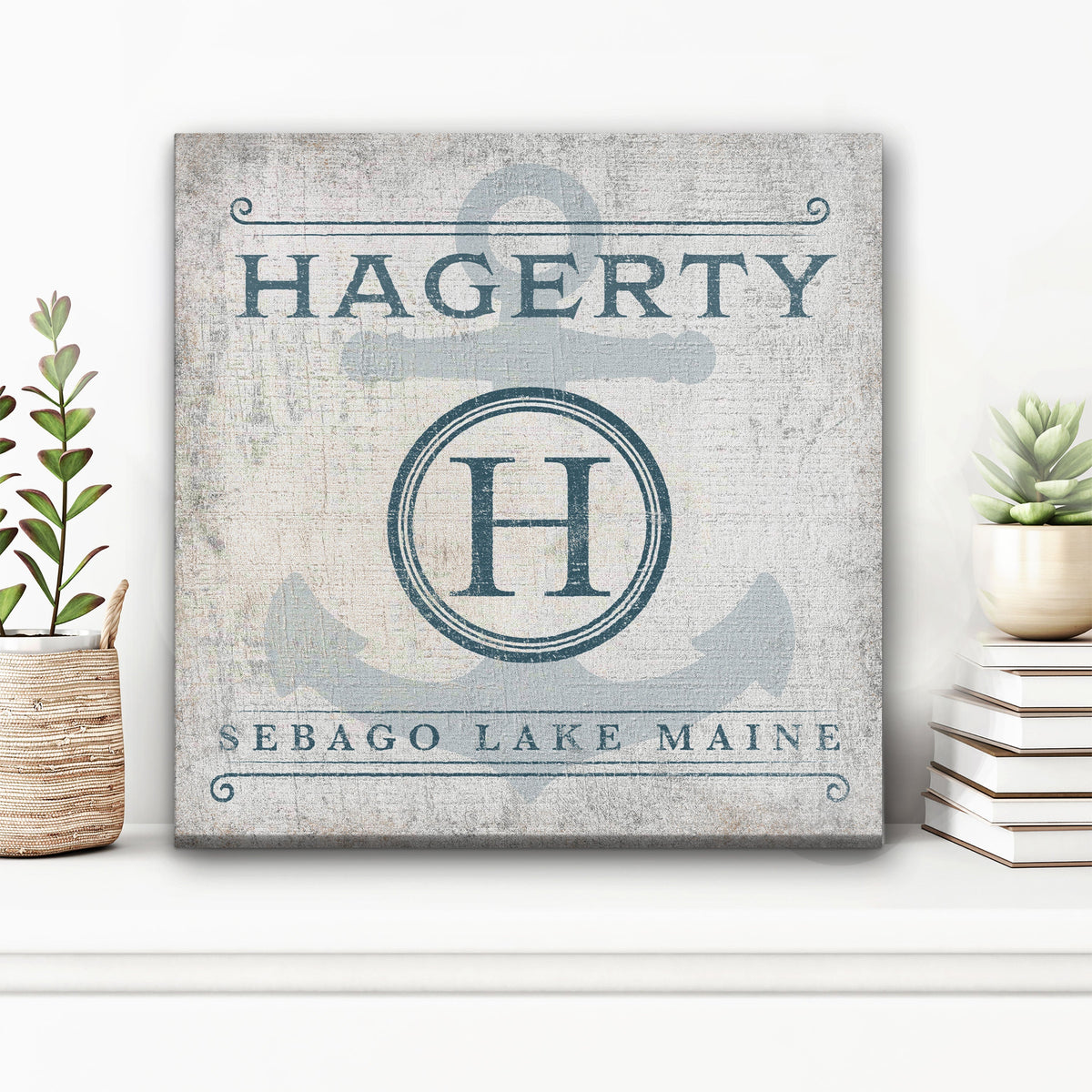 Anchor Monogram Canvas displaying "Hagerty" across the top, a bold "H" inside a circular monogram badge over a large faded anchor, and "Sebago Lake Maine" along the bottom, in slate blue on a distressed cream background