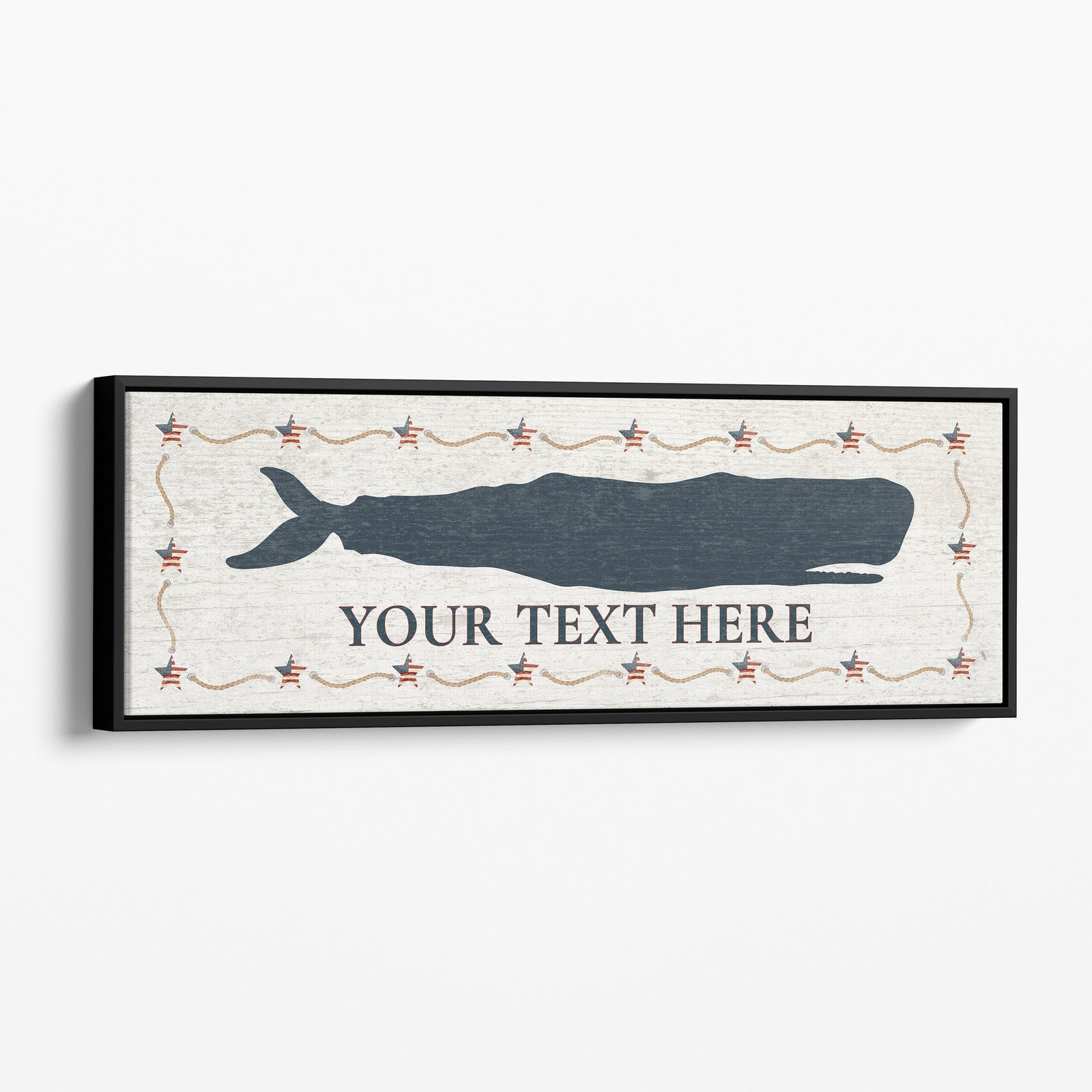 Personalized Framed Whale Canvas Sign displaying a large navy blue sperm whale silhouette above custom text on a distressed white background with an Americana star and rope border, in a black floating frame mounted on a white beadboard wall