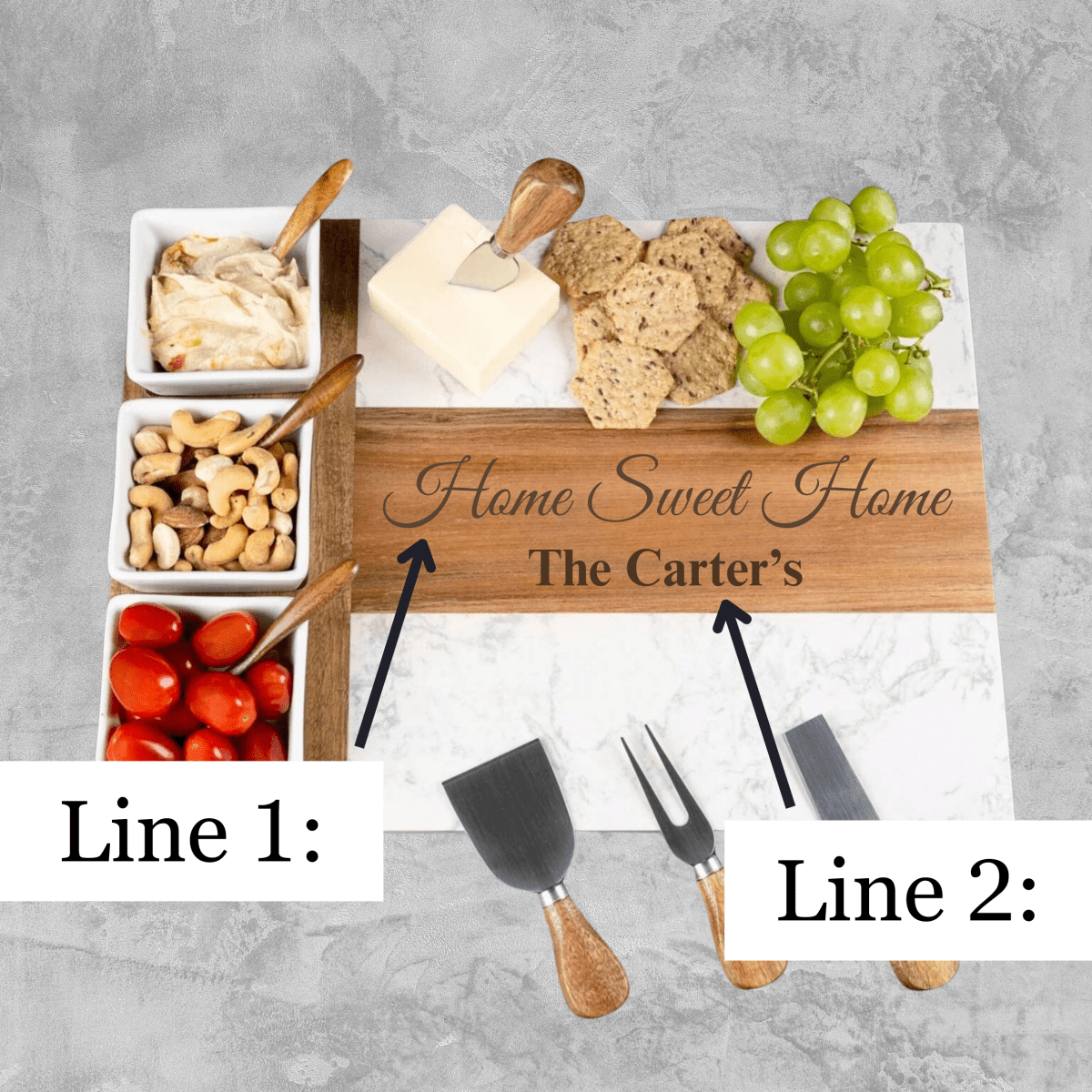 Personalized charcuterie board with sample engraving "Home Sweet Home The Carter's", white ceramic bowls, cheese, crackers, grapes, nuts, and wooden serving utensils on marble and wood base