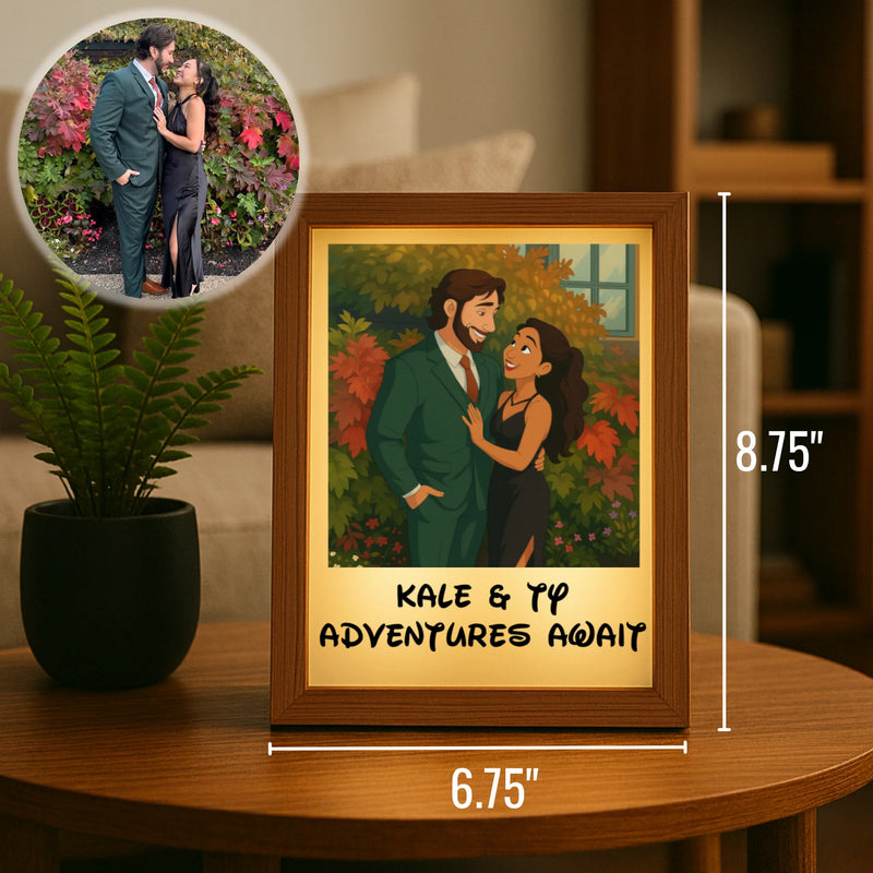 Framed cartoon portrait with wood border showing couple with sample names "KALE & TYP" and text "ADVENTURES AWAIT" below, displayed on wooden table next to potted plant, measuring 6.75" wide by 8.75" tall