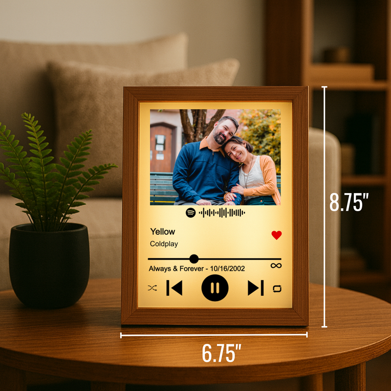 Personalized Spotify song frame with wood border displaying couple photo, song title "Yellow" by Coldplay, sample date "Always & Forever - 10/16/2002", and music player controls on yellow background, shown with dimensions 6.75" by 8.75