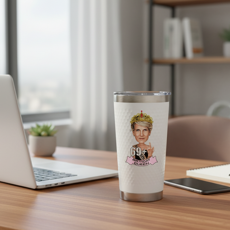 White 20oz insulated tumbler with stainless steel base, displayed on wooden desk with sample cartoon portrait design showing age 69 and "Birthday Queen" text