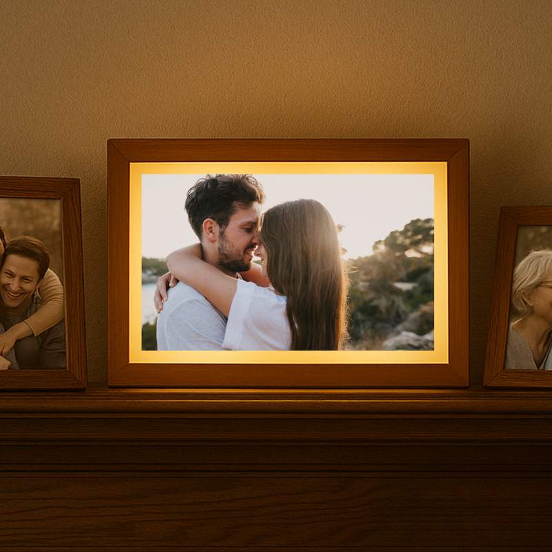 Three wood-framed light-up photo frames displayed on a wooden shelf, with the center frame showing a couple embracing outdoors with a yellow mat border and illuminated backing.