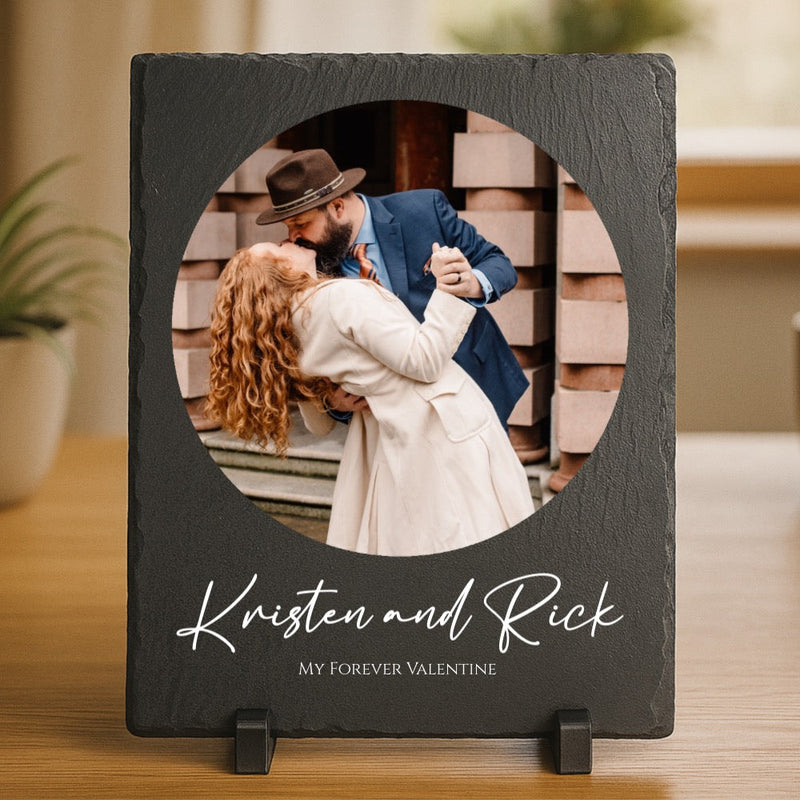 Black slate photo frame with circular cutout displaying couple dancing, personalized with sample names "Kristen and Rick" and text "MY FOREVER VALENTINE" engraved below