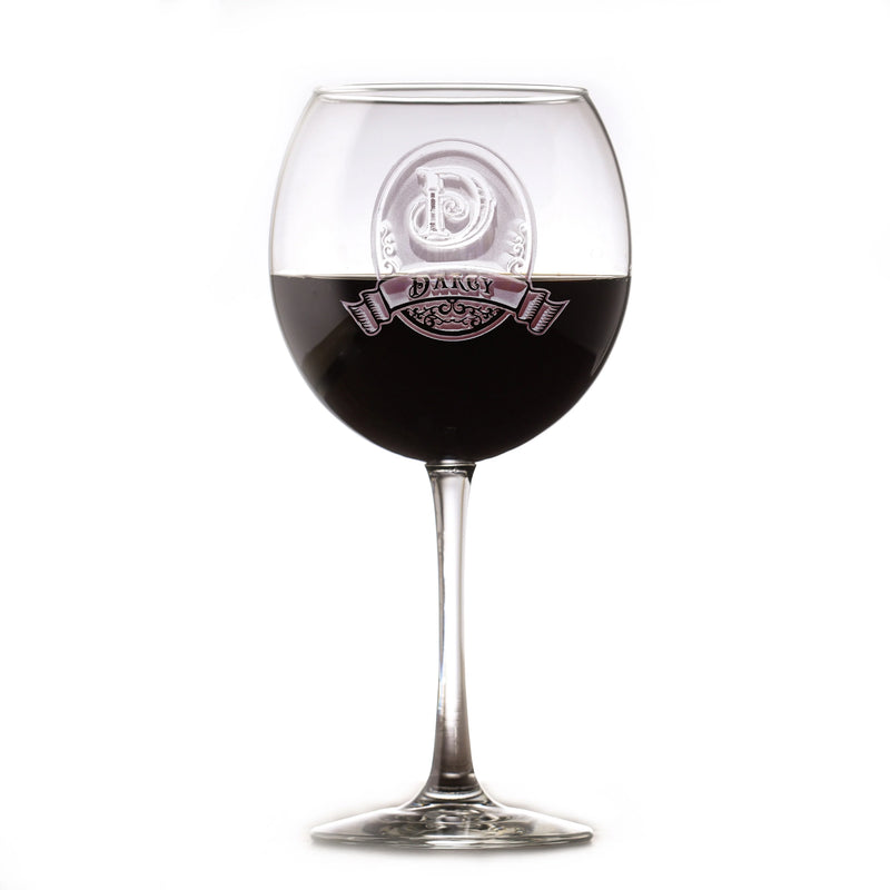 Wine glass filled with dark liquid, deep-etched with sample monogram "D" and ornate banner labeled "DARCY" on the bowl