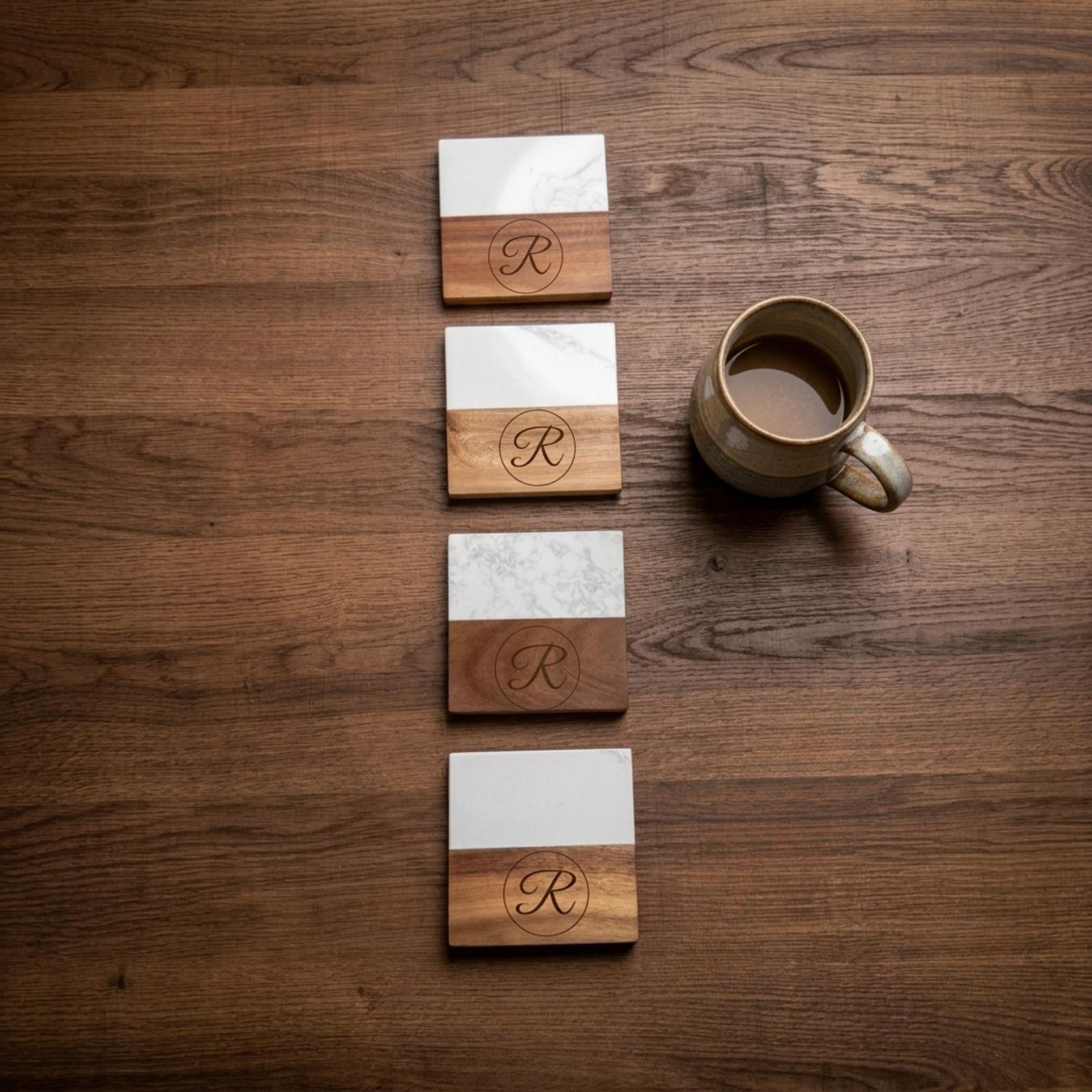 Four square coasters with marble top and wood base engraved with sample family name and establishment year, displayed on wooden table.