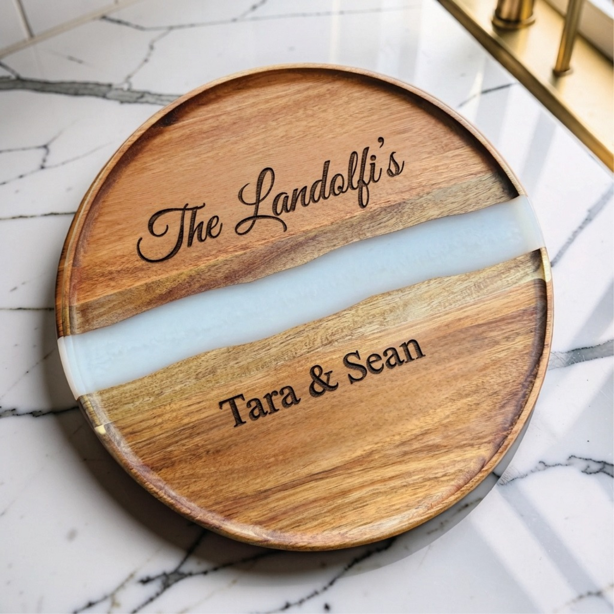 Round acacia serving board with a pearl white resin river, engraved The Landolfi's in script and Tara &amp; Sean below