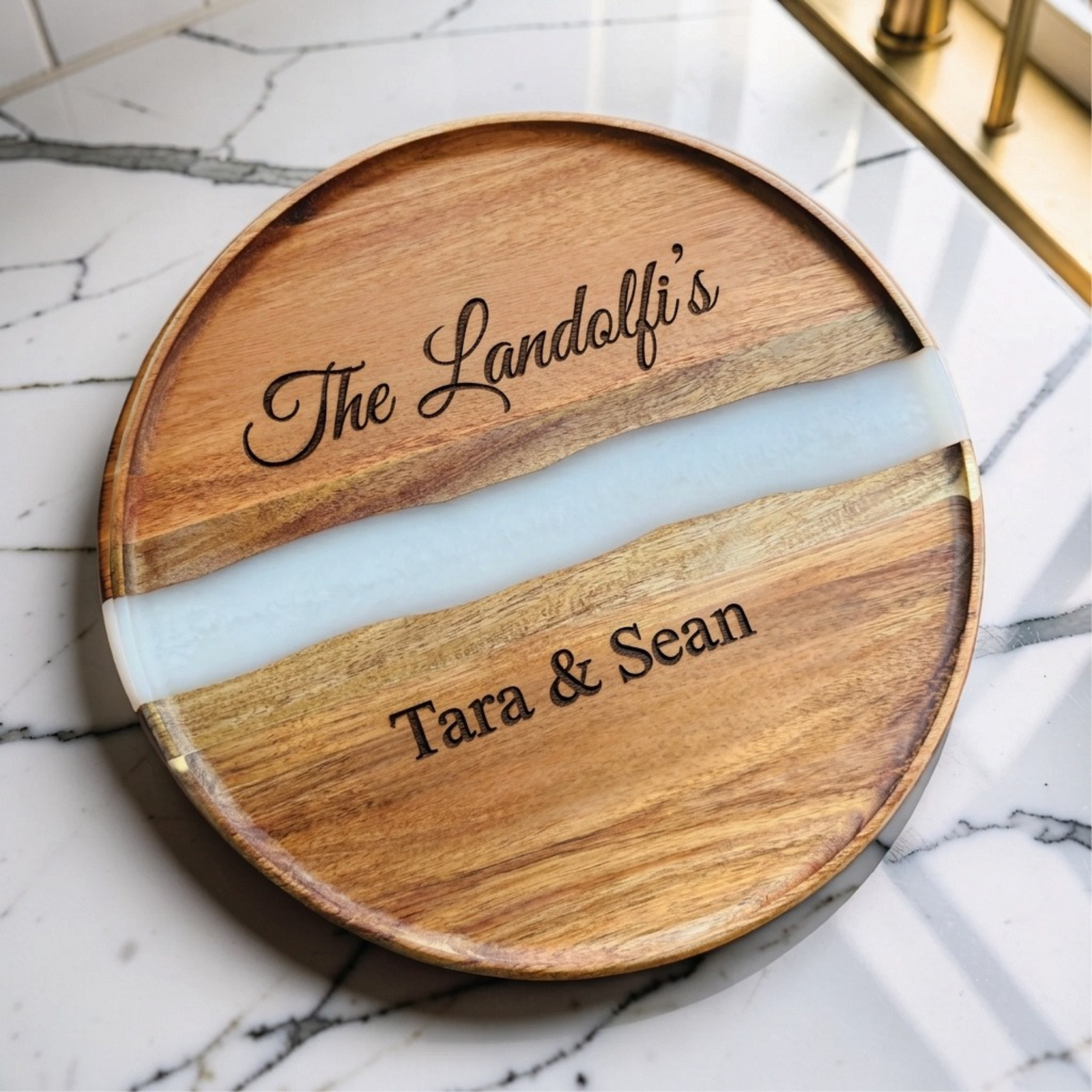 Round acacia serving board with a pearl white resin river, engraved The Landolfi's in script and Tara & Sean below