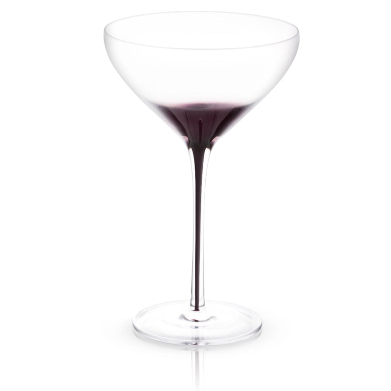 Clear martini glass with black swan-shaped stem, filled with dark purple cocktail, shown against white background