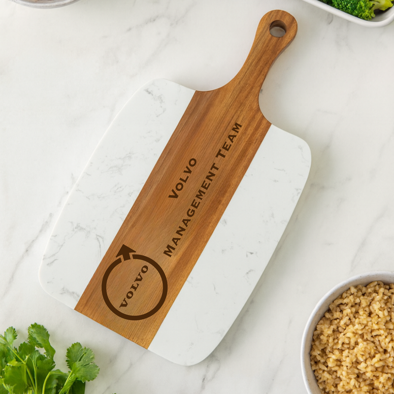 Acacia wood and marble serving board engraved with sample text "VOLLIO MANAGEMENT TEAM" and circular logo design, displayed on marble countertop