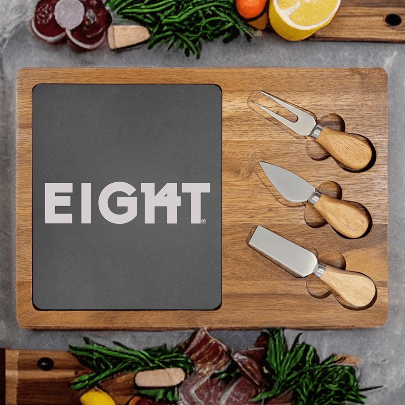 Wooden entertainer's board with slate inset engraved with sample logo "EIGHT" and three cheese knives with wooden handles positioned on the right side