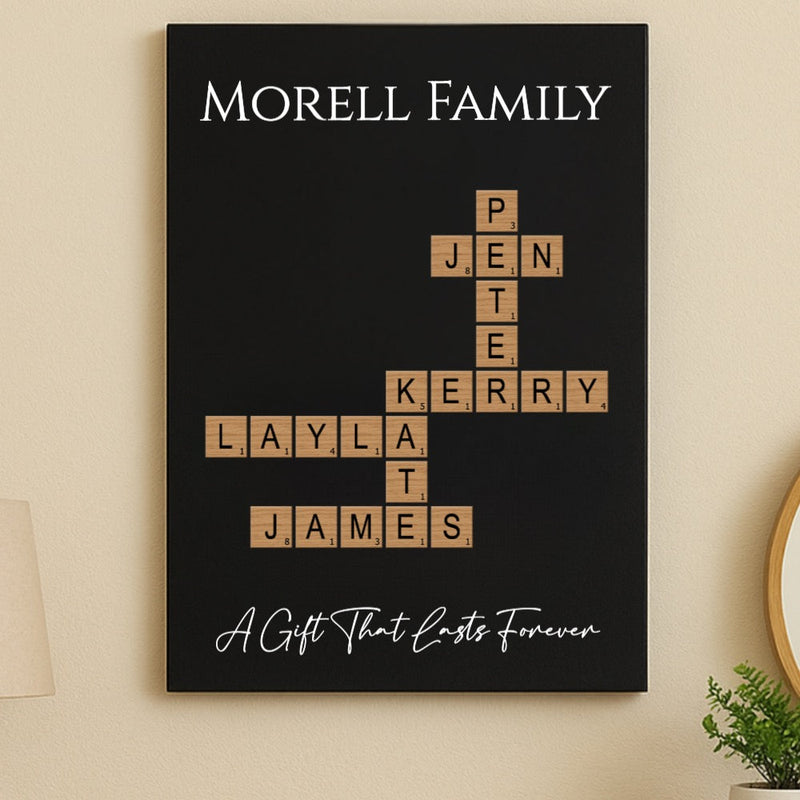 Black wall art with sample family names "MORELL FAMILY" arranged in crossword style using wooden Scrabble-inspired tiles, with tagline "A Gift That Lasts Forever" below.