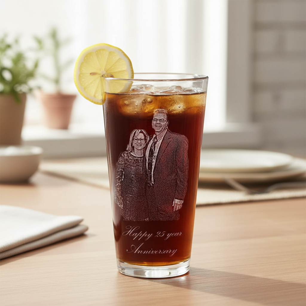 Pint glass filled with cola and ice, garnished with a lemon slice, engraved with sample photo of a couple and text reading "Happy 25 year Anniversary