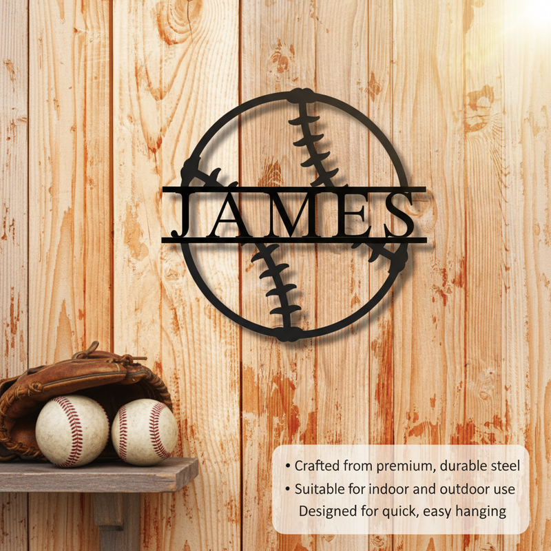 Black steel baseball sign with sample name "JAMES" engraved horizontally across center, displayed on natural wood wall with baseballs and glove below