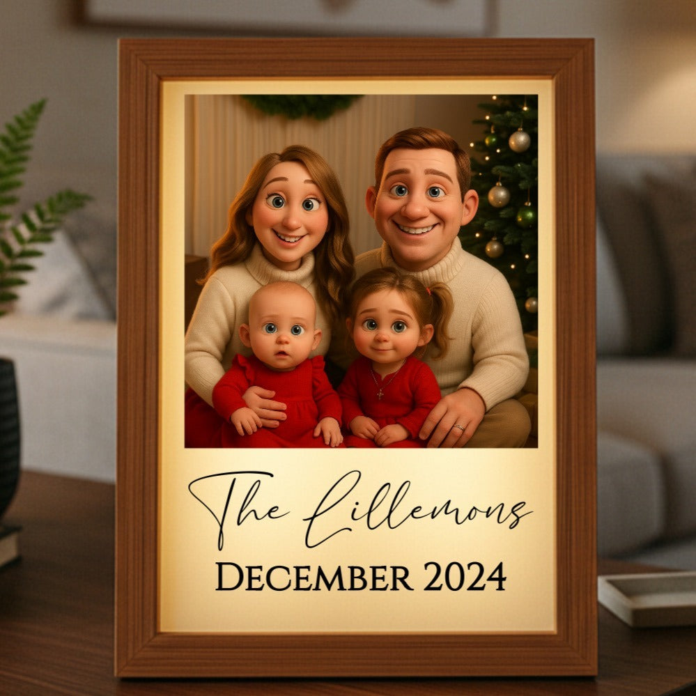 Wooden framed light box displaying animated family portrait with sample text "The Lillemons" and "December 2024" on cream background, showing two adults and two children in holiday sweaters with Christmas tree behind