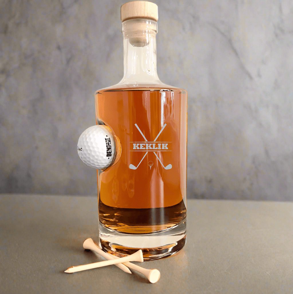 Personalized glass golf decanter with an embedded golf ball, engraved with "KEKLIK" and crossed golf clubs design. Willow and HIve
