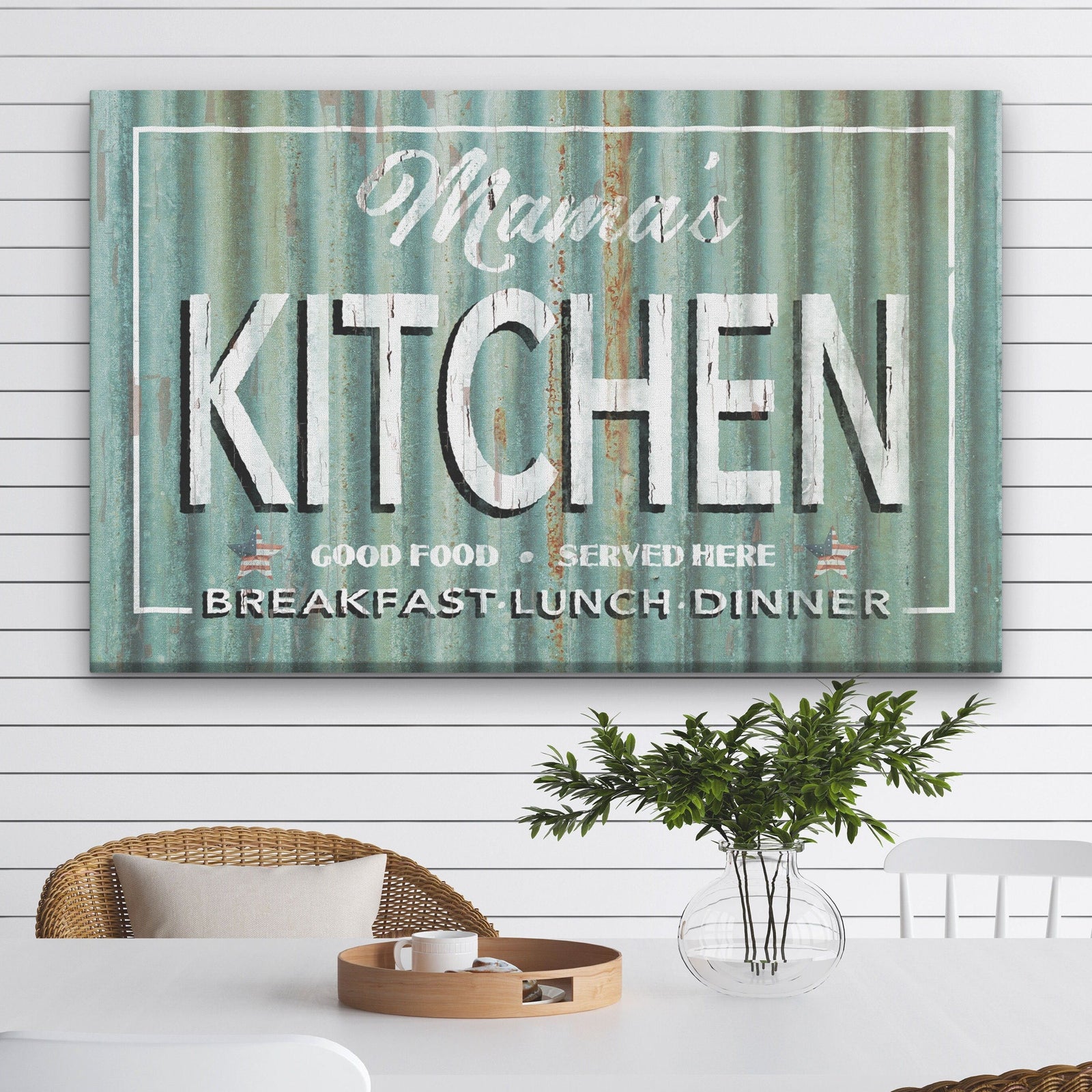 Tin Roof Kitchen Canvas showing "Mama's Kitchen" in bold white lettering above "Good Food · Served Here" and "Breakfast · Lunch · Dinner" on a distressed rust corrugated metal background, mounted above a wooden kitchen counter with white bowls and eucalyptus