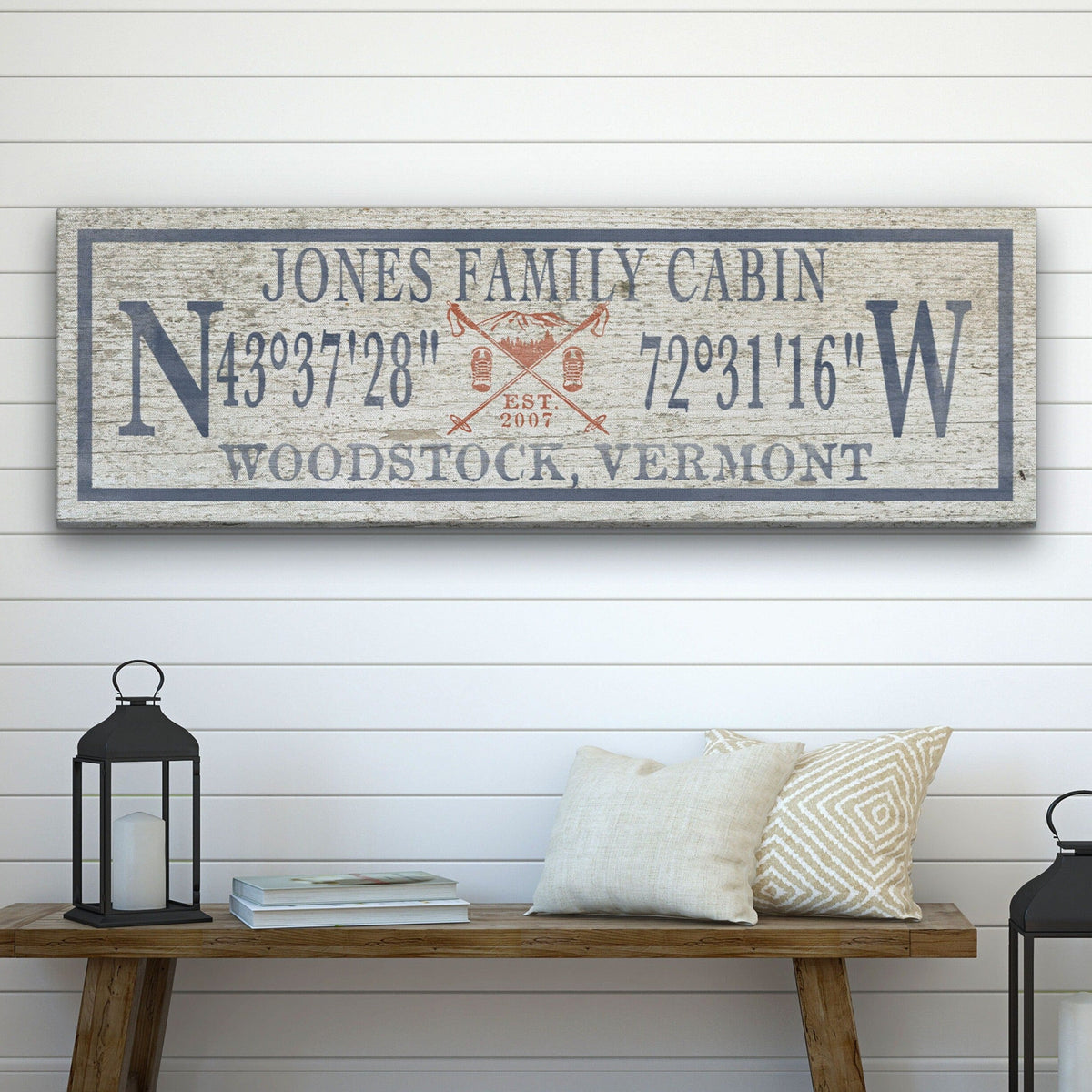 Personalized Canvas Ski Lodge Sign displaying "Jones Family Cabin" above GPS coordinates flanked by large N and W compass letters, with a crossed ski poles and mountain illustration reading "Est. 2007" and "Woodstock, Vermont" at the bottom, on a distressed cream wood background with a slate border